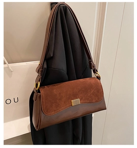 Detail of dark brown vintage underarm bag with matte suede texture and gold metal buckle
