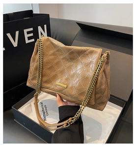Détail d'un sac à chaîne en cuir matelassé marron avec boucle dorée et bandoulière