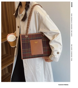 Detail of tartan wool tote bag with leather logo patch and metal chain strap