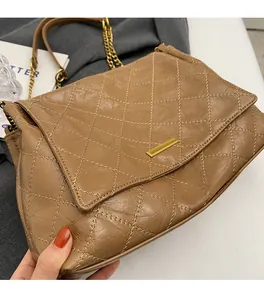 Détail de la texture en cuir matelassé marron et de la boucle en métal doré