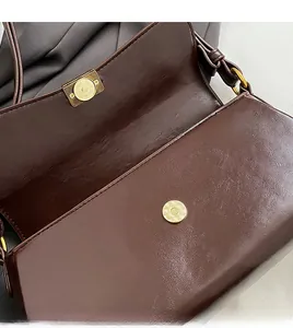 Close-up of premium gold-toned magnetic hardware on brown litchi textured leather bag