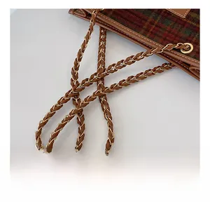 Detail of the woven chain strap with golden metal rings and retro plaid fabric texture