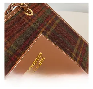 Detail of checkered woolen fabric with leather patch and gold chain strap on tote bag