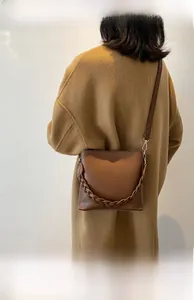Sac seau en cuir marron avec détail tressé porté par un mannequin en vue latérale