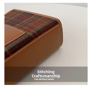 Close-up of white stitching craft on caramel leather and plaid wool tote bag