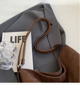 Detail of a brown suede crossbody bag showing the soft texture and silver buckle