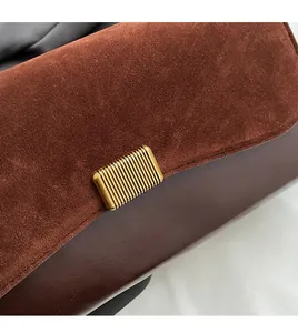Detail of dark brown leather underarm bag with gold textured buckle and suede texture