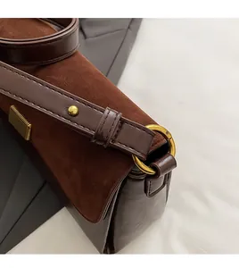 Detail of detachable gold ring hook and brown leather strap with rivets on shoulder bag