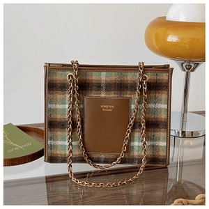 Close-up of retro plaid woolen tote bag with brown leather trim and metallic chain strap