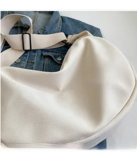 Détail du sac bandoulière en toile blanche montrant le tissu sergé et la sangle réglable
