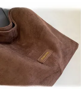 Detail of dark brown faux suede texture and leather fashion tag on the tote bag