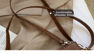 Gros plan d'une bandoulière en cuir marron avec boucle dorée sur un blazer à carreaux