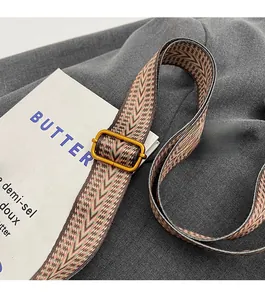 Détail d'une bandoulière tissée réglable avec motif vagues et boucle en métal doré