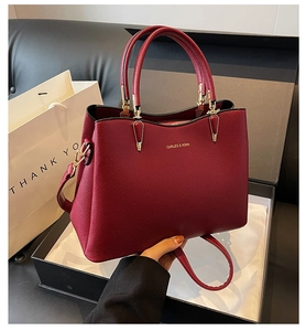 Detail view of burgundy pebble leather wedding handbag with gold hardware and top handle