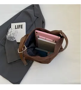 Detailed view of the spacious interior of a brown suede tote bag with books and a tablet