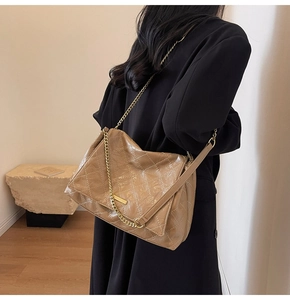 Gros plan du sac bandoulière matelassé marron avec chaîne dorée et fini brillant