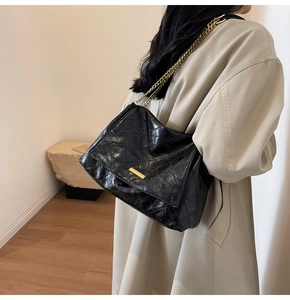 Sac à bandoulière matelassé noir avec chaîne dorée porté par un mannequin de profil