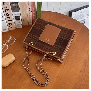 Detail of tweed tote bag with check pattern, leather patch, and woven chain strap