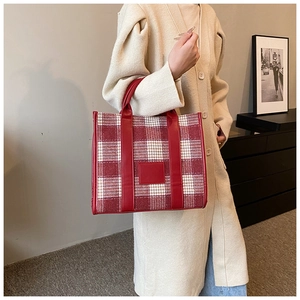 Detail der rot-weißen Hahnentritt-Tasche mit Lederriemen an einem Strickjacken-Modell