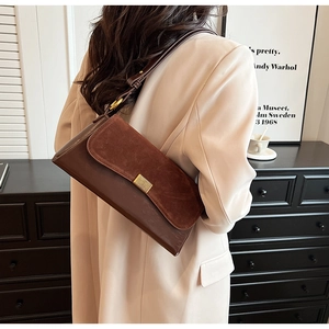 Detail of vintage brown leather underarm bag with gold buckle on beige blazer