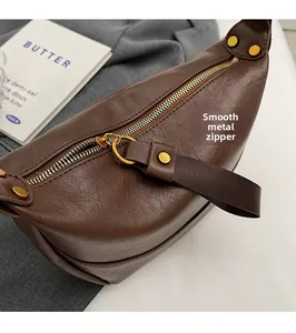 Détail de la fermeture dorée et texture cuir grainé sur un sac bandoulière marron