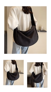 Détail d'un grand sac en toile noire en forme de croissant avec bandoulière large