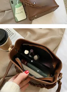 Détail du sac seau en cuir marron avec poignée tressée et compartiments intérieurs spacieux