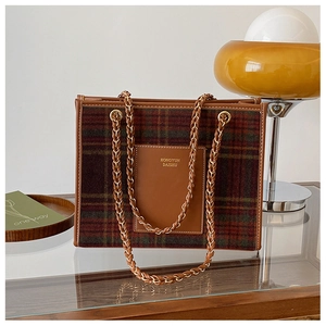 Detailed view of checkered wool tote bag with leather pockets and chain strap on a cabinet