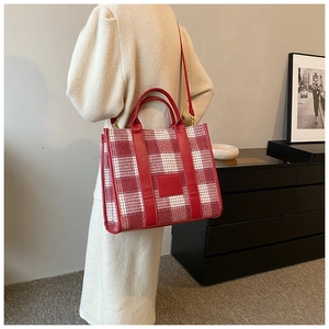 Detailaufnahme der rot-weißen Tragetasche mit Ledergriffen an einem Model im Herbstoutfit