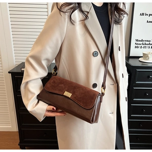 Detail showing the brown frosted suede flap and gold metal buckle on the shoulder bag