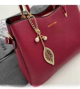 Detail of dark red lychee grain leather handbag with gold leaf and pearl charm