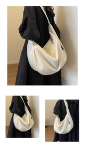 Détail du sac dumpling en toile blanc cassé avec large bandoulière et fermeture éclair