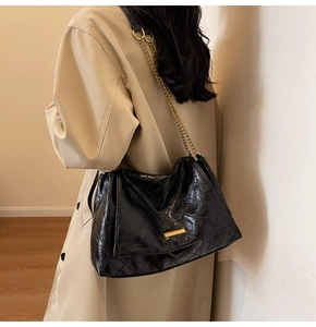 Détail du sac matelassé noir avec chaîne dorée et finition en cuir brillant chic