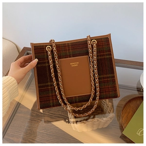Detail of green plaid wool tote with leather pocket and gold brand lettering