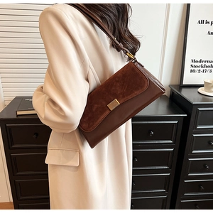 Close-up of a brown suede and leather underarm bag with a golden metallic clasp