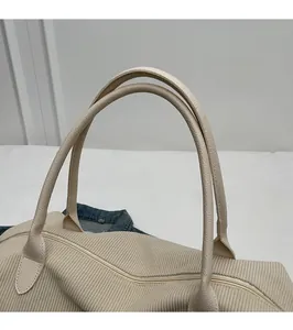 Close-up of durable corduroy texture and faux leather handle on beige travel bag