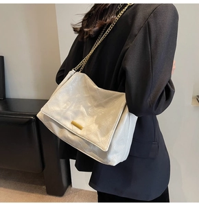 Gros plan d'un sac matelassé crème en similicuir brillant avec boucle dorée