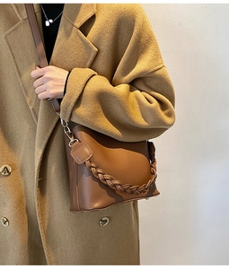 Détail d'un sac seau marron avec poignée tressée épaisse et bandoulière réglable chic