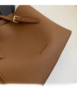 Détail du sac cabas en cuir marron à motif litchi avec lettrage et boucle dorée