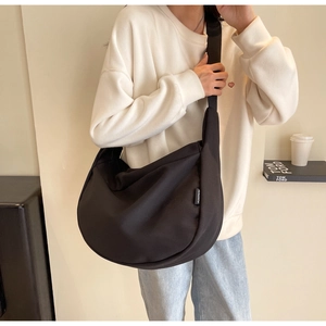Détail de la texture du sac croissant en toile noire et de la large bandoulière