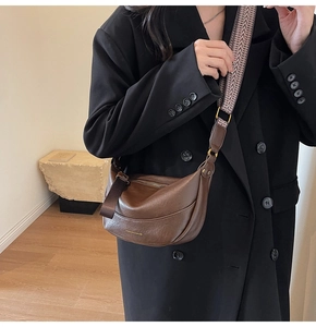 Détail sac croissant en cuir marron avec bandoulière tissée géométrique et fermeture