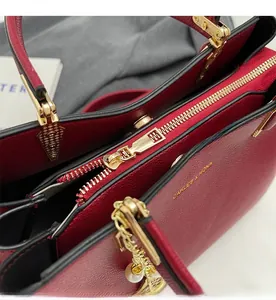 Detail of red lychee grain leather wedding bag featuring smooth gold zipper and pearl charm