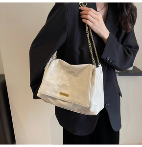Gros plan du sac à bandoulière matelassé crème avec détails en métal doré