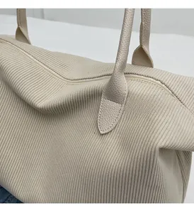 Detail of corduroy fabric texture and leather handle on a large cream tote bag