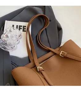 Détail du sac cabas en cuir grainé marron avec bandoulières réglables et boucles dorées