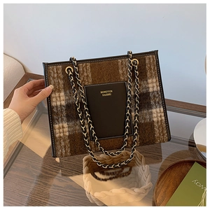 Detail of checkered woolen tote bag with leather chain handle and brand logo plate