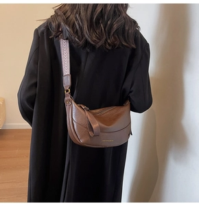 Détail du sac demi-lune en similicuir marron avec large bandoulière jacquard et logo