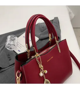 Detail of red pebbled leather bridal handbag with gold hardware and pearl leaf charm