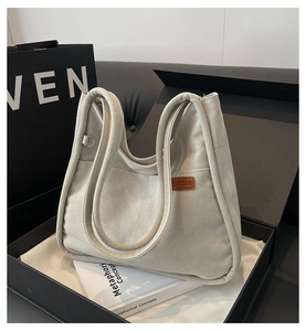 Detail of canvas bucket bag with leather logo tag in a premium gift box presentation