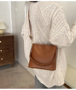 Sac seau en cuir marron avec détail tissé porté par un mannequin en décor intérieur